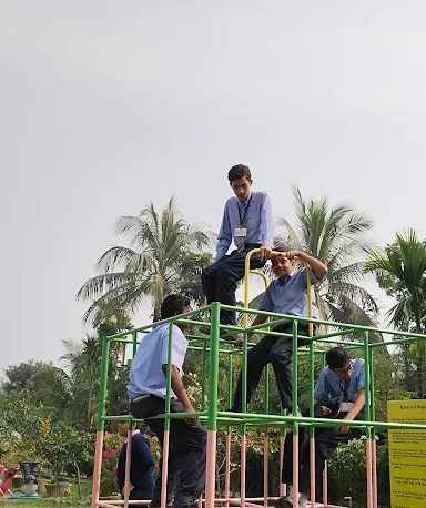 School students in uniform climbing and sitting on a colourful metal climbing frame