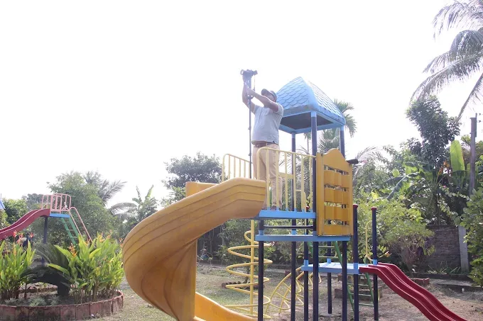 A blue-roofed play tower with a yellow spiral slide, ladders and a red slide
