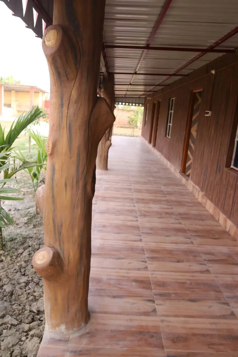 A long covered veranda with tree-trunk style pillars and wood-effect floor tiles